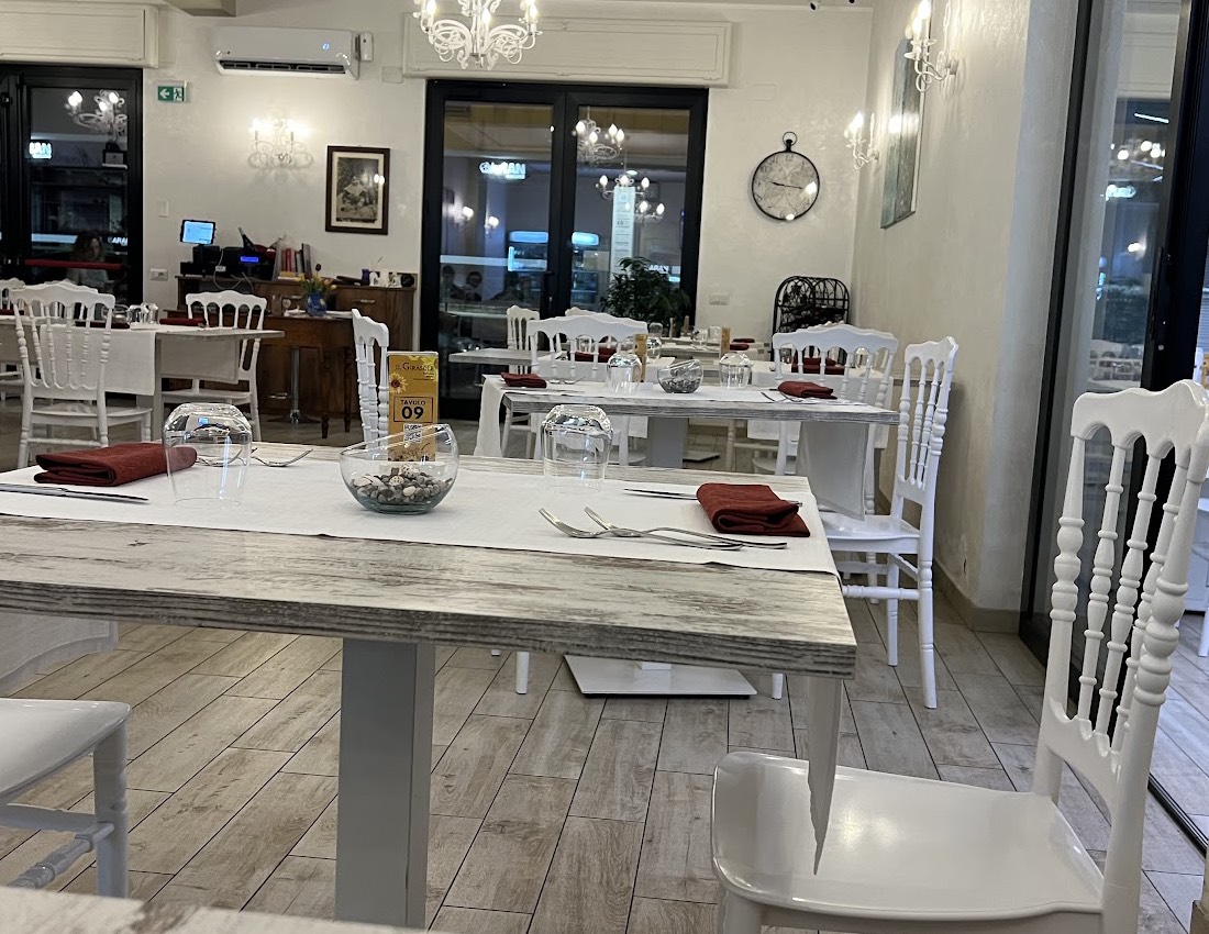 La sala del ristorante Il Girasole, con tavoli apparecchiati e sedie bianche